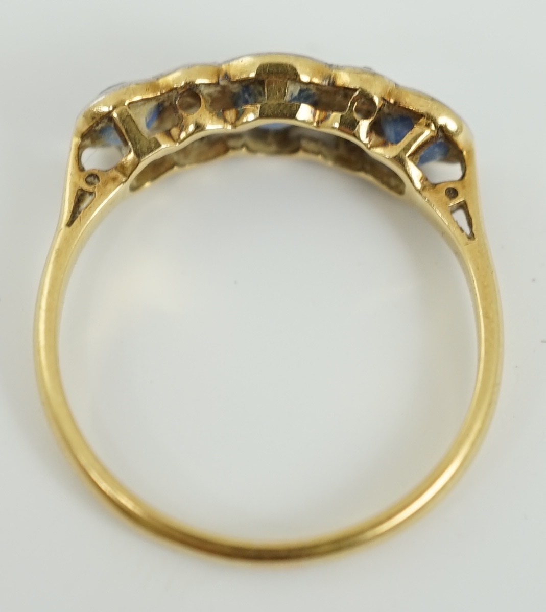 A 1920's 18ct gold and platinum, millegrain set three stone sapphire and four stone diamond half hoop ring